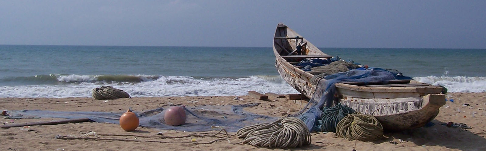 Zoomed in view of a rowboat on the coast of Legon. The rowboat is surrounded by fishing nets and ropes.